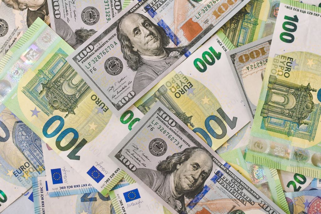 Draufsicht auf ein buntes Gemisch aus Euro-Banknoten und US-Dollar-Scheinen. Ein Symbolbild für das Währungsrisiko, Wechselkursschwankungen und deren Einfluss auf die Rendite im ETF-Depot.