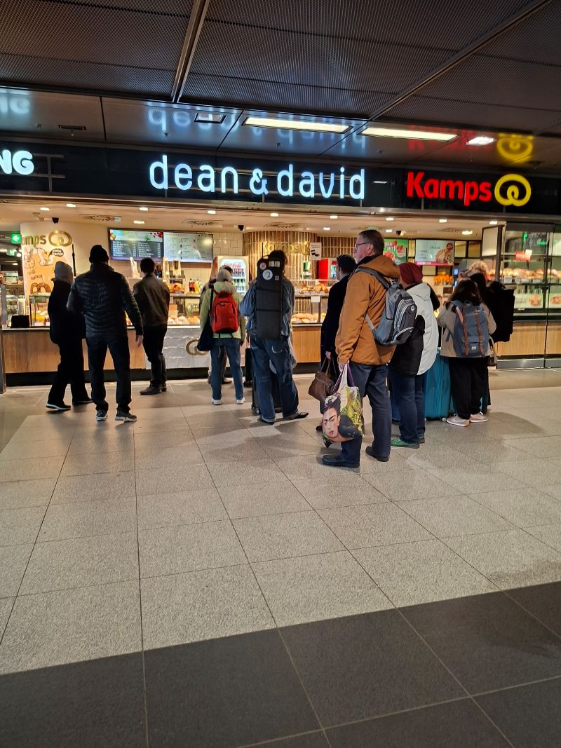 Menschenschlange am Morgen vor den Bäckerei- und Kaffeeständen im geschäftigen Berliner Hauptbahnhof.