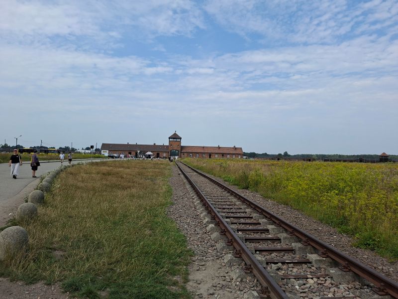 Blick entlang der Eisenbahnschienen auf das markante Eingangstor des ehemaligen Konzentrations- und Vernichtungslagers Auschwitz-Birkenau.