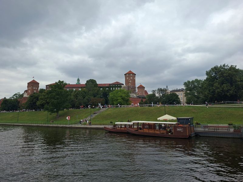 Ansicht der imposanten Burg Wawel in Krakau vom Fluss Weichsel aus bei leicht bewölktem Himmel.