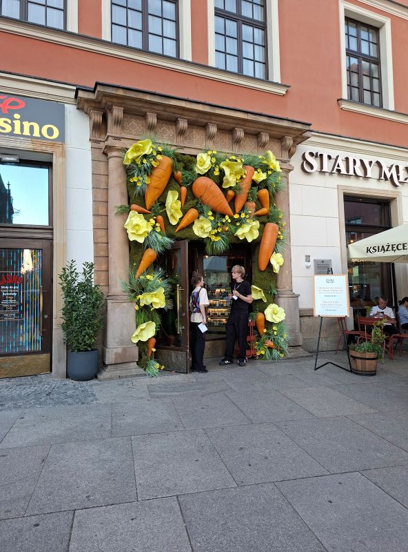 Mit übergroßen Karotten und gelben Blumen aufwendig dekorierter Eingang eines Restaurants in Breslau.
