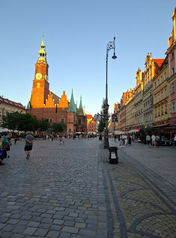 Blick über das gepflasterte Areal des Breslauer Ryneks mit historischem Rathaus im Abendlicht.