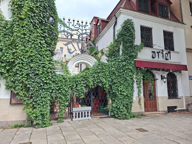 Fassade des jüdischen Restaurants Ariel im Krakauer Stadtteil Kazimierz mit Efeubewuchs und einer Menora über dem Eingang.