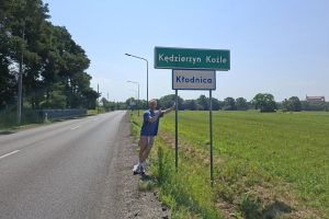 Der Blog-Autor neben dem Ortsschild der polnischen Stadt Kędzierzyn-Koźle an einer Landstraße.