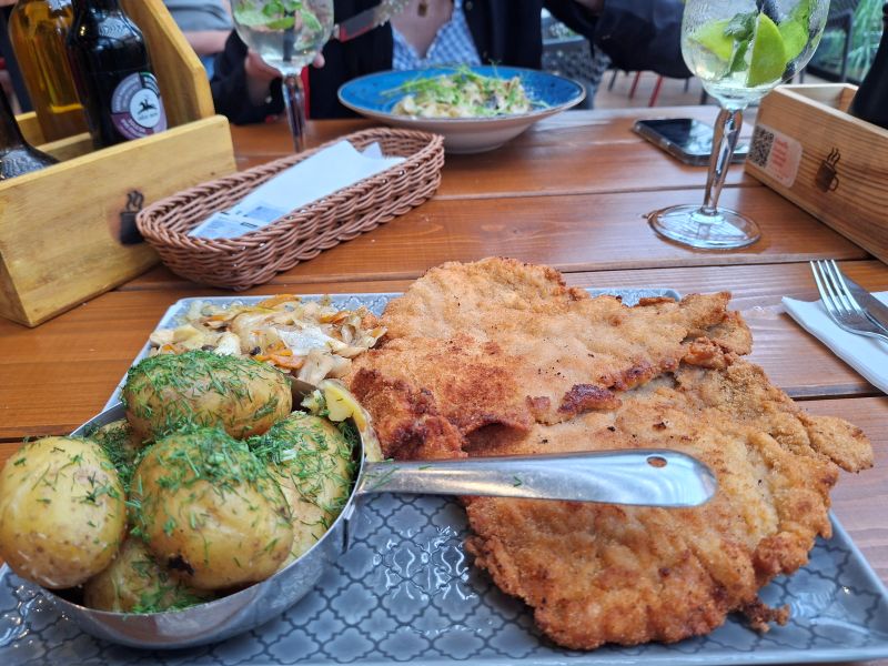 Großzügig serviertes Schnitzelgericht mit Dillkartoffeln und Beilagen auf einem gedeckten Restauranttisch.