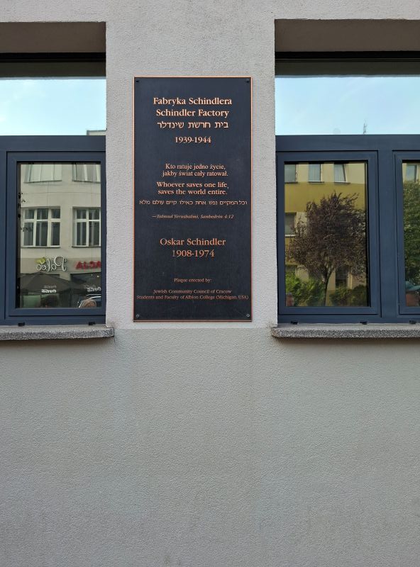 Bronzene Gedenktafel mit mehrsprachigen Inschriften an der Außenwand der ehemaligen Fabrik von Oskar Schindler.